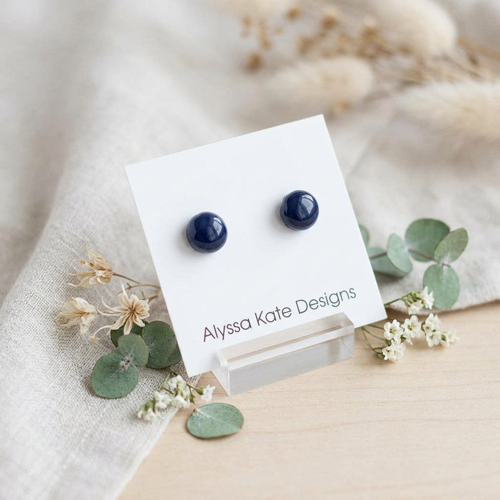 A pair of small round dark blue stud earrings.