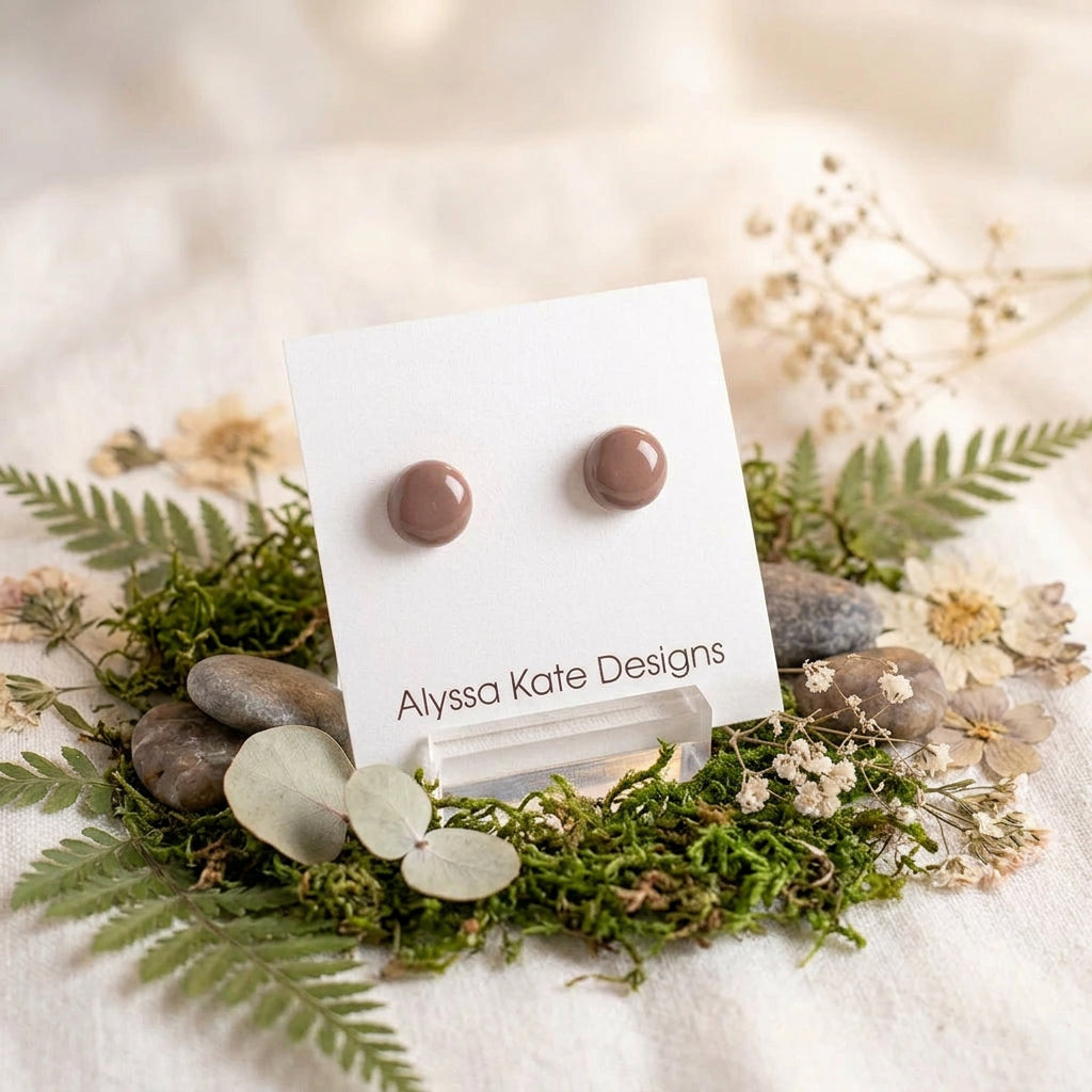 A pair of small round stud earrings in a warm brown color.