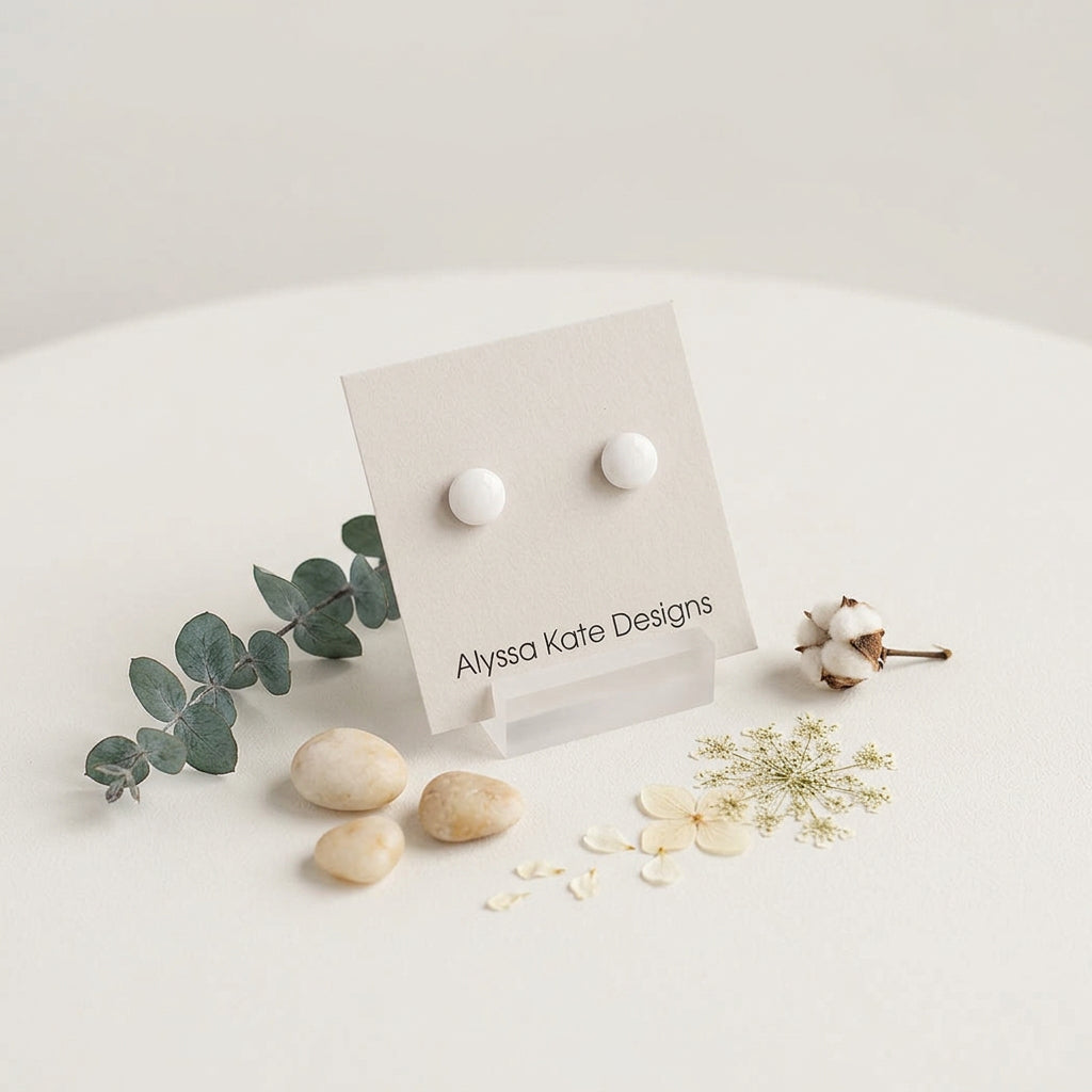 A pair of small round white stud earrings.
