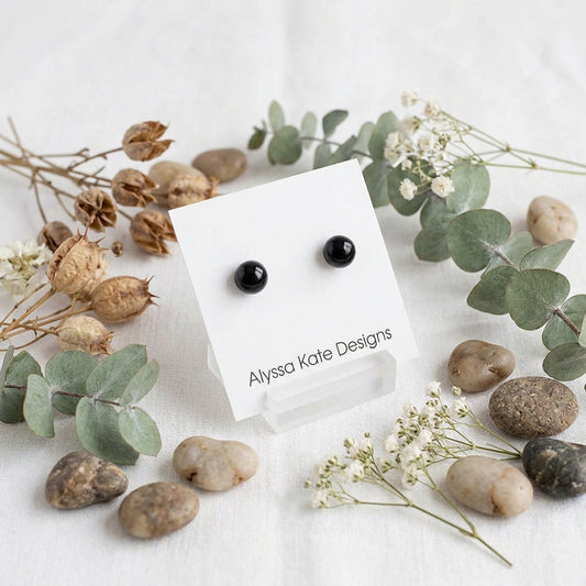 A pair of small black round stud earrings.