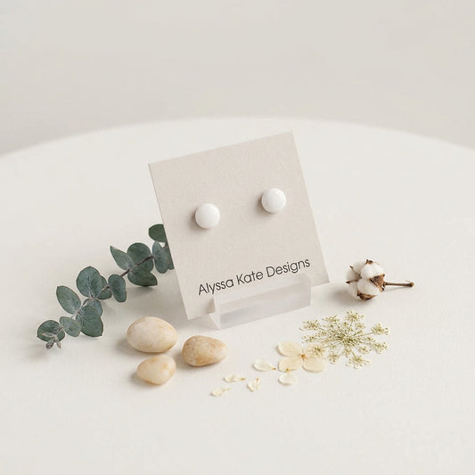 A pair of small round white stud earrings.