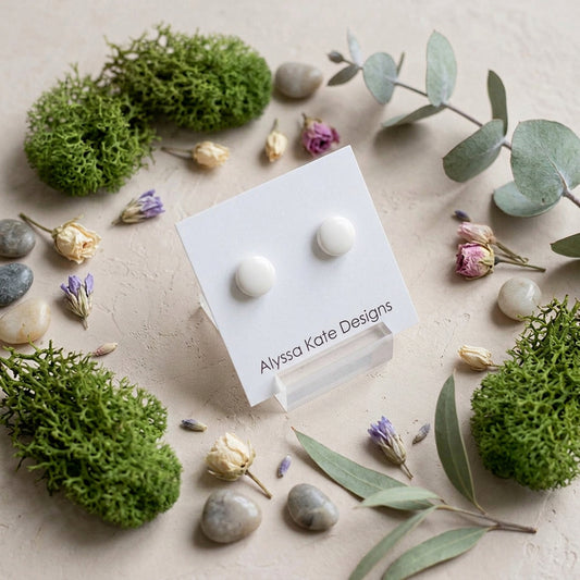 A pair of small round stud earrings in a warm off-white or cream color.