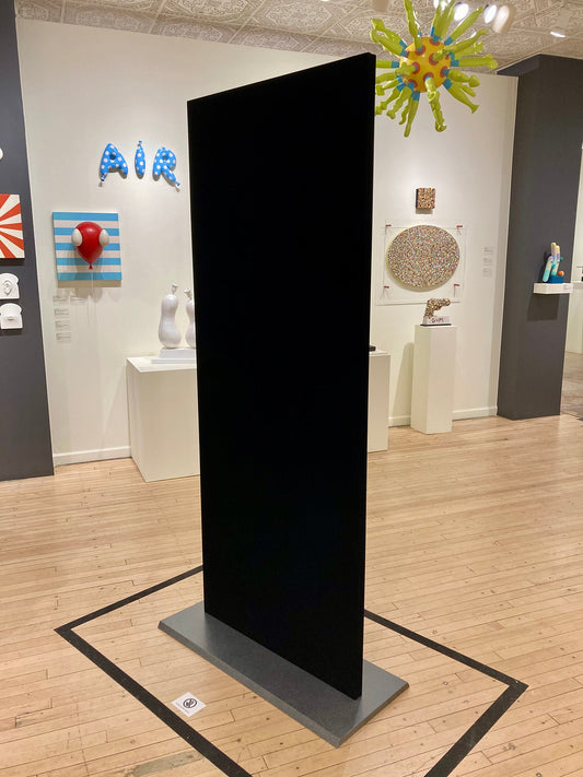 Wooden sculpture of a completely black door on a metal stand. 2020 80"x32"x1.5" Singularity Black ™ wrapped wood armature by Sean O'Meallie