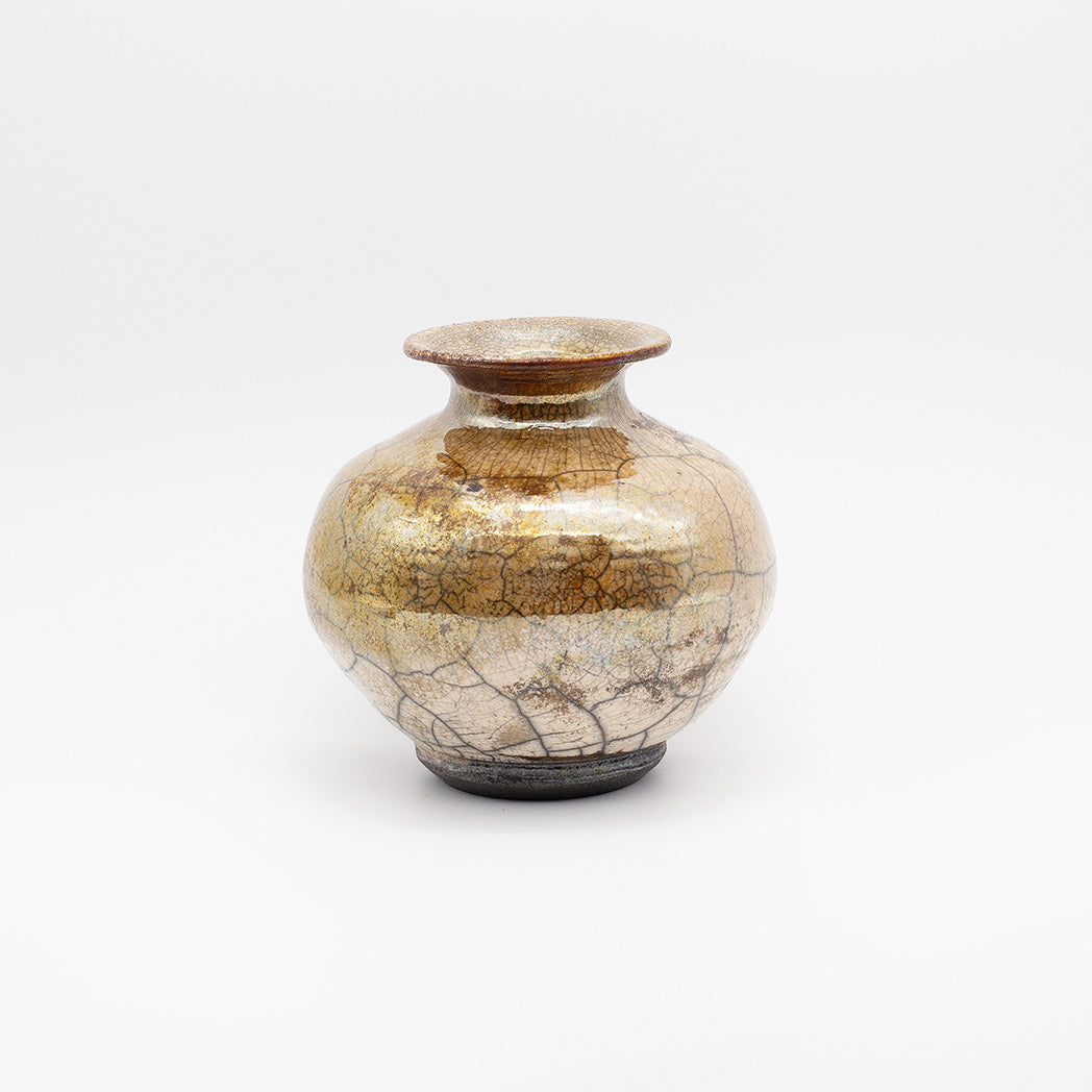 A small ceramic vase with a rounded body, flared rim, and dark base, covered in a glossy crackled glaze with gold, brown, and beige tones.
