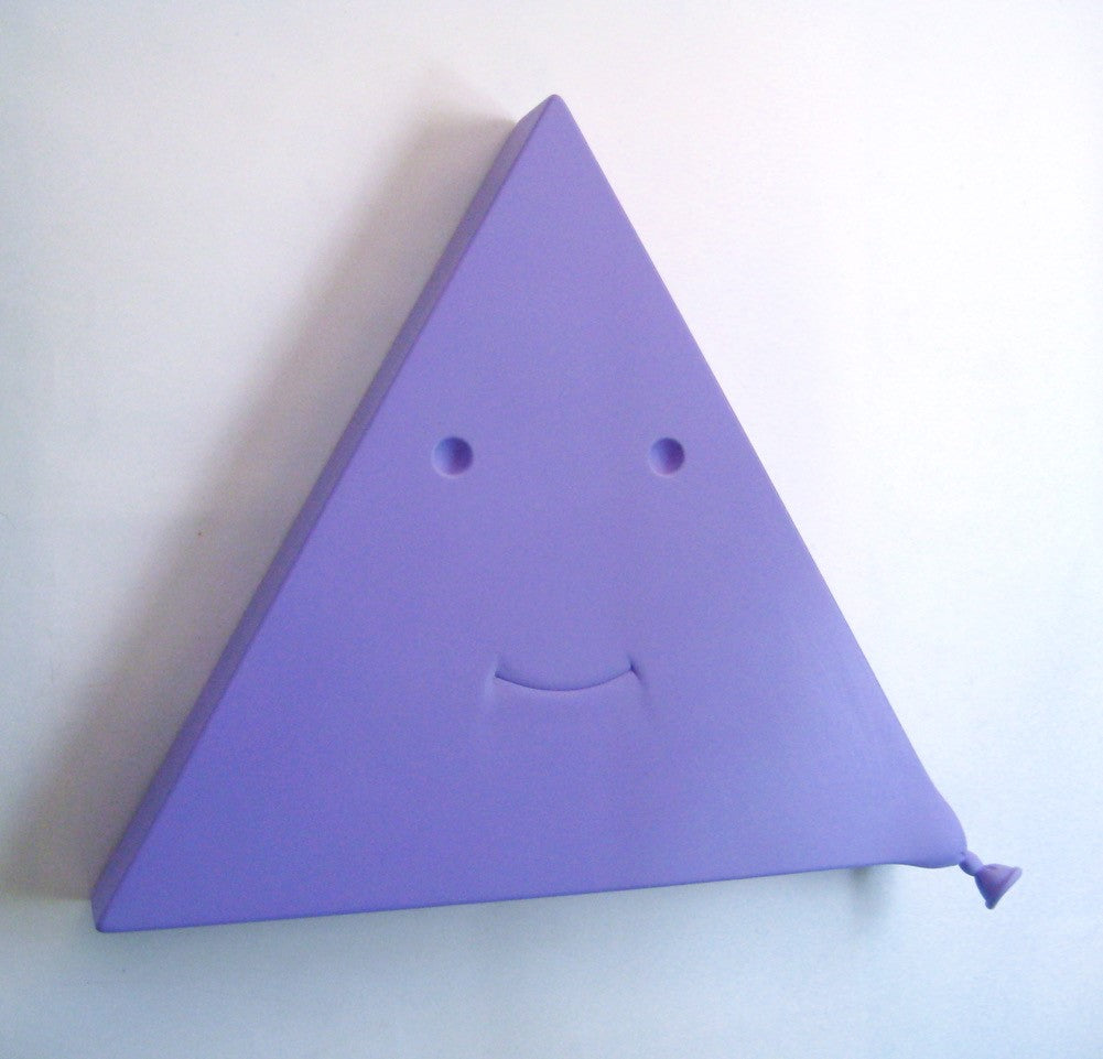 Wooden sculpture in the shape of a triangle in a bright shade of purple. There are two eyes and a smiling mouth on the triangle forming a face. There is a balloon tip on the bottom right side of the triangle giving the impression that the triangle is a balloon. 2022 27”x31”x6” painted wood by Sean O'Meallie